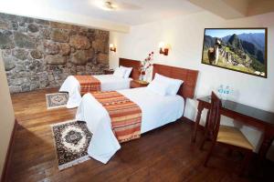 Habitación de hotel con 2 camas y pared de piedra. en Siete Ventanas, en Cusco