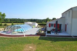 eine Terrasse mit einem Gewächshaus neben einem Gebäude in der Unterkunft L'EDEN DE LA HAUTE FORET in Mervent