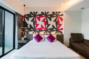een slaapkamer met een groot bed met roze kussens bij Hotel J Residence Pattaya - SHA Extra Plus in Pattaya