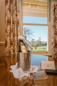 - une bouteille de vin dans un seau sur une table avec une fenêtre dans l'établissement Chateau Yering, à Yarra Glen