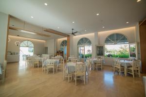 a dining room with white tables and chairs and windows at Hotel Alkionis in Moraitika