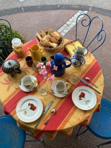 una mesa con platos de comida y una cesta de pan en La Sarrasine, en Villes-sur-Auzon