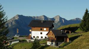 una casa en una colina con montañas en el fondo en Almhotel Fichtenheim en Berg im Drautal