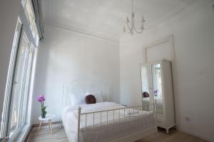 ein weißes Schlafzimmer mit einem weißen Bett und einem Spiegel in der Unterkunft George Enescu Suites in Bukarest