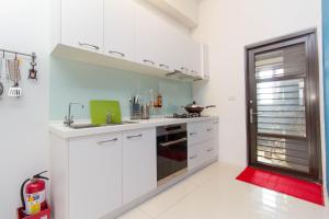 a kitchen with white cabinets and a red rug at 曉翠軒親子民宿 in Wujie