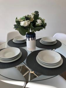 a glass table with plates and a vase of flowers at Skyview Apartment in Liverpool in Liverpool +2 photos