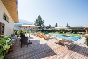 een terras met stoelen en parasols naast een zwembad bij Hotel Kranebitt B&B in Bressanone