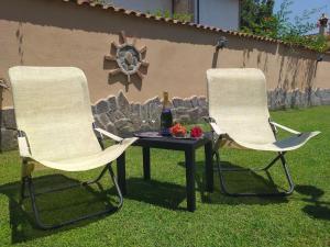 twee stoelen en een tafel met een fles wijn bij Villa Vittorio in Infernetto