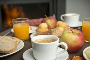 uma mesa com uma chávena de café, maçãs e queques em Hotel portico em Fonsagrada