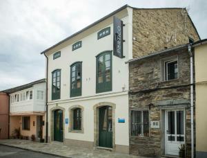 a white building with green doors on a street at Hotel portico in Fonsagrada