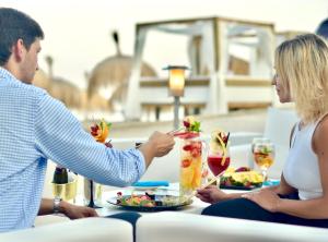 a man and woman sitting at a table with food and drinks at Gran Hotel Guadalpín Banus in Marbella