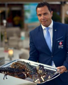 a man in a suit holding a lobster on a tray at Gran Hotel Guadalpín Banus in Marbella