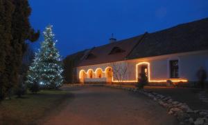 Un árbol de Navidad delante de un edificio blanco en Sörényes Udvarház, en Pénzesgyőr