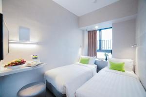 a hotel room with two beds and a bowl of fruit at Hotel Ease Mong Kok in Hong Kong