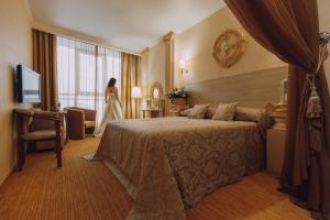 a hotel room with a bed and a woman standing in a window at Olymp Kazan in Kazan