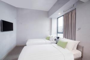a hotel room with two beds and a flat screen tv at Hotel Ease Mong Kok in Hong Kong