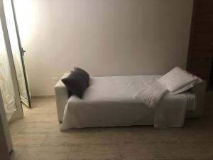 un letto con lenzuola bianche e cuscini neri in una stanza di B&B San Vincenzo a Scafati