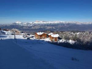 a snow covered hill with houses and mountains in the background at les 7 laux immobilier chalet B in Prapoutel