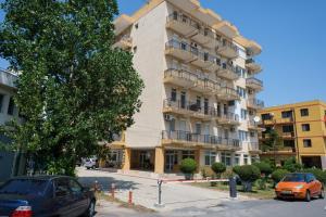 ein hohes Gebäude mit davor geparkt in der Unterkunft Saona Residence Mamaia Nord in Mamaia Nord – Năvodari