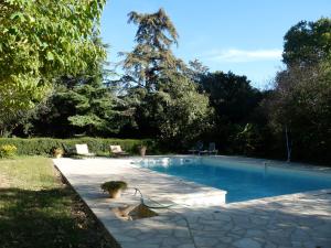 einen Pool in einem Garten mit einem Baum im Hintergrund in der Unterkunft Les Esclots , Nîmes, Gîtes 4 personne in Générac