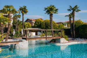 una piscina en un complejo con palmeras en Palazzo della Scala Spa Hotel Suites & Apartments, en Lazise
