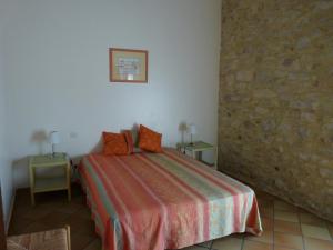 ein Schlafzimmer mit einem Bett und einer Steinmauer in der Unterkunft Les Esclots , Nîmes, Gîtes 4 personne in Générac