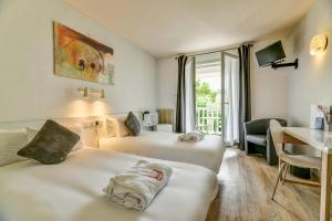 um quarto de hotel com duas camas e uma secretária em Logis Thermal em Saubusse