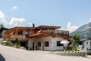 ein Haus mit einem Balkon, einem Tisch und einem Sonnenschirm in der Unterkunft Ferienwohnung Heissl in Fieberbrunn