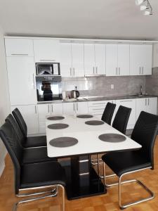 a kitchen with a white table and black chairs at Apartman Taša in Banja Luka