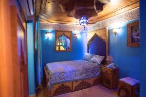 a bedroom with blue walls and a bed and a table at Riad Mehdi Meknès in Meknès