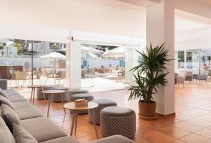 una sala de estar con sofás y mesas y un patio. en Hotel Palia Dolce Farniente, en Cala d´Or