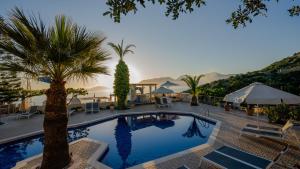 una piscina con palmeras, mesas y sillas en Panorama Villas - Adults Only, en Agios Nikolaos