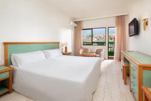 a hotel room with a large white bed and a window at Sol Puerto de la Cruz Tenerife in Puerto de la Cruz