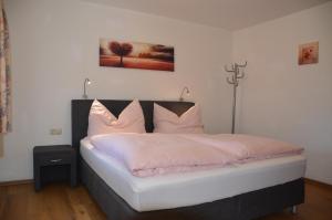 1 dormitorio con 1 cama con sábanas y almohadas blancas en Appartements Gadenstätter, en Maria Alm am Steinernen Meer