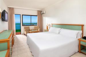 a bedroom with a large white bed and a desk at Sol Puerto de la Cruz Tenerife in Puerto de la Cruz
