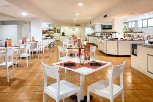 a restaurant with white tables and white chairs at Sol Puerto de la Cruz Tenerife in Puerto de la Cruz
