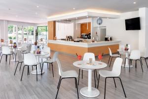 a restaurant with white tables and chairs and a kitchen at Sol Puerto de la Cruz Tenerife in Puerto de la Cruz