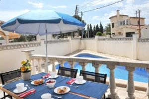 een blauwe tafel met een parasol op een balkon met een zwembad bij Guti in L'Escala