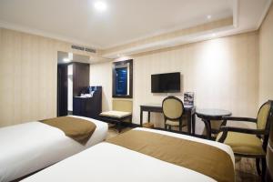 Habitación de hotel con 2 camas, escritorio y TV. en Golden Boutique Hotel Melawai, en Yakarta