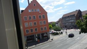 a tall red building on a city street with a road at Appartament im Herzen von Nürnberg in Nürnberg