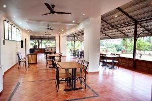 a restaurant with tables and chairs and a ceiling fan at Riverside Inn in Koynanagar
