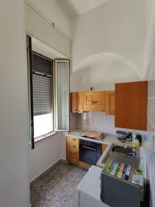 cocina con armarios de madera, fregadero y ventana en Miramare Vacanze Apartment, en Santa Cesarea Terme