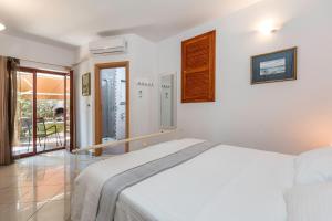 a white bedroom with a bed and a balcony at Meri in Premantura