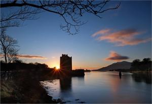 a castle in the middle of a river at sunset at Narrow Water Castle Self Catering Accommodation in Warrenpoint