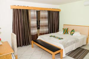 a bedroom with a bed with a wooden headboard and curtains at LT Aparthotel in Praia