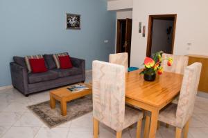 a dining room with a wooden table and a couch at LT Aparthotel in Praia