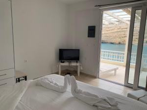 um quarto com uma cama, uma televisão e uma varanda em Bella Vista Luxury Apartment em Matala