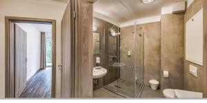 a bathroom with a glass shower and a sink at Nova City Apartments in Budapest