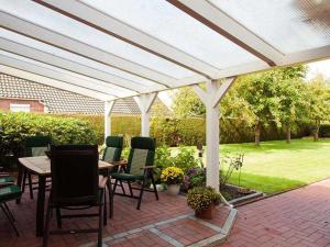 uma pérgola branca com cadeiras e mesas num pátio em Ferienwohnung Sonnenberg, 25502 em Weener