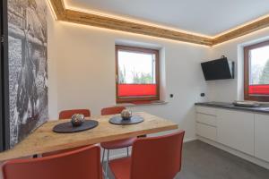 une salle à manger avec une table en bois et des chaises rouges dans l'établissement Ferienwohnungen Alpentraum - Ferienhaus Schmid, à Oberstdorf